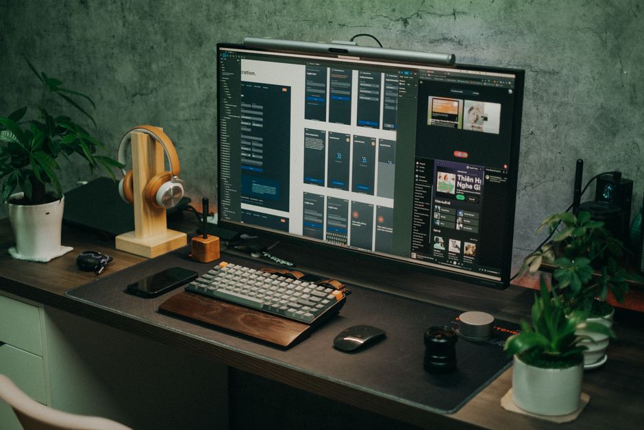 Sleek home office setup s velikim monitorom, tipkovnicom i biljkama na stolu