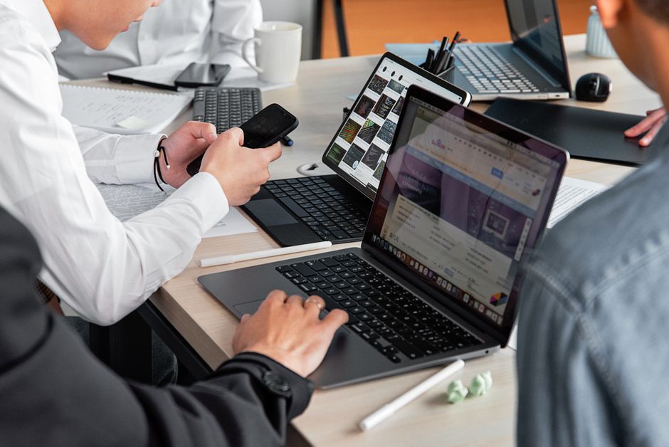 Profesionalci u modernom uredu razgovaraju s laptopima i pametnim telefonima